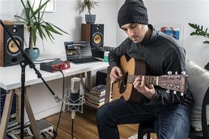 Man playing acoustic guitar in home studio