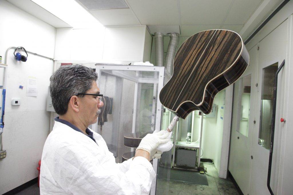 Employee at Taylor Guitars holding a guitar body ready to get sprayed