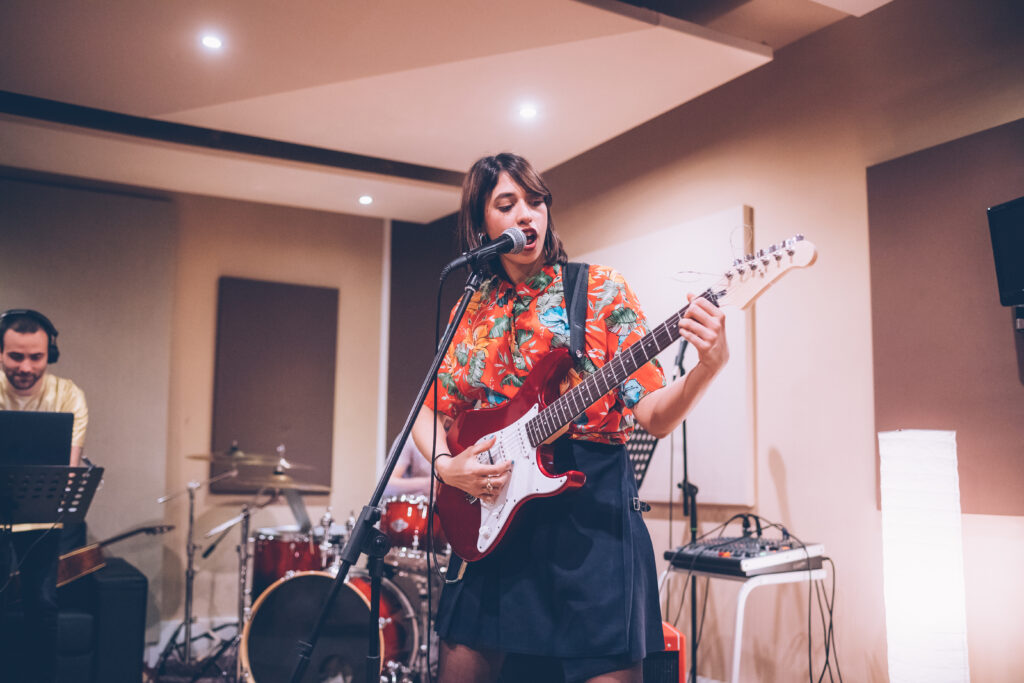 Young woman musician playing electric guitar singing