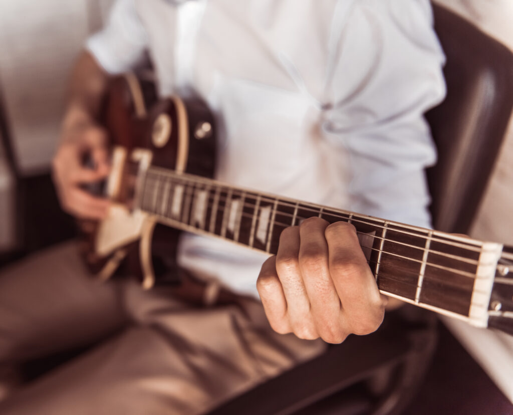 Cropped image of young businessman playing guitar in his office during the break.