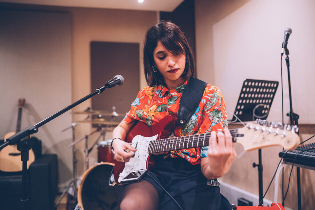 Young woman musician playing electric guitar.
