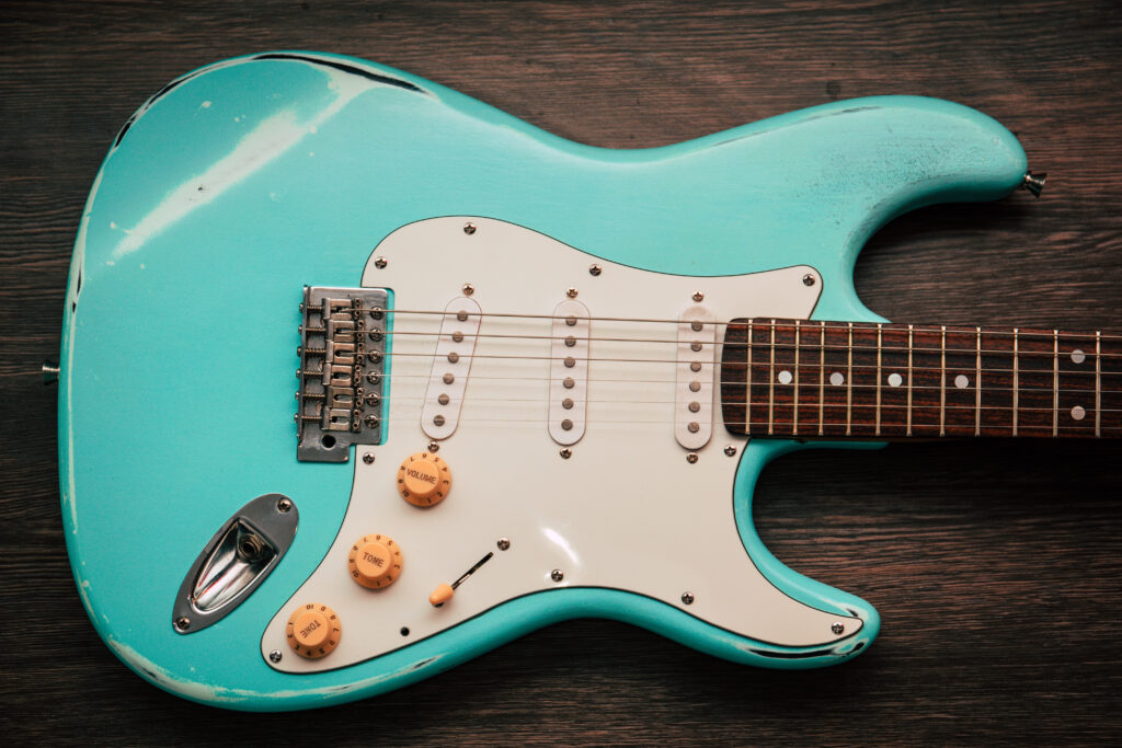 A blue Stratocaster on a wooden table on its side.