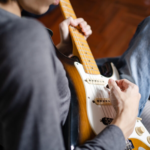 Man sitting down and playing an electric guitar.