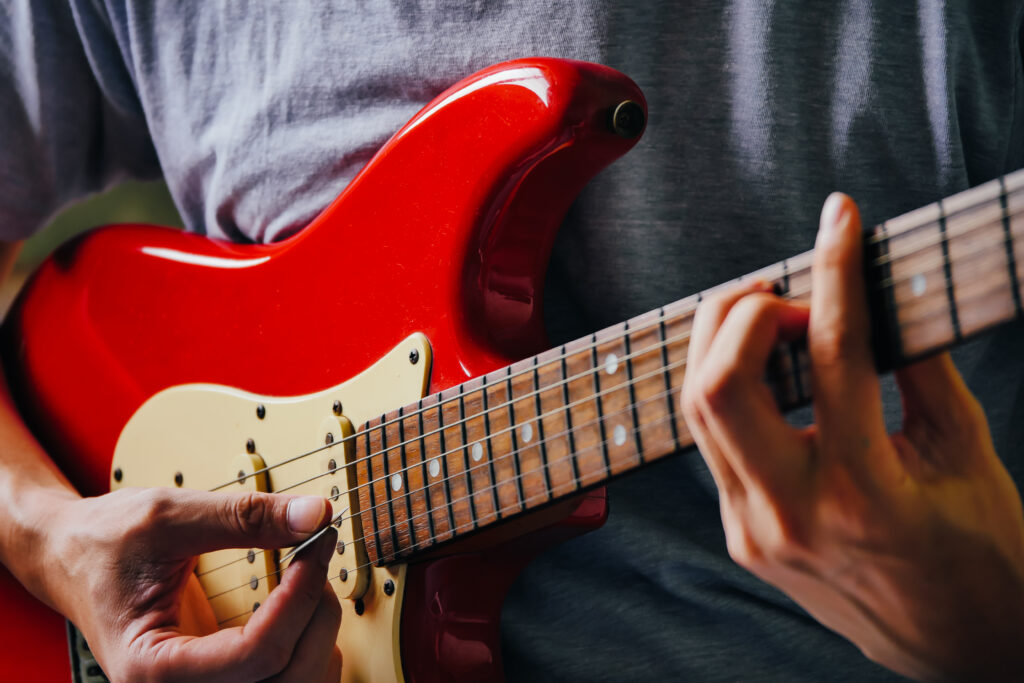 Man playing a red Fender Stratocaster.
